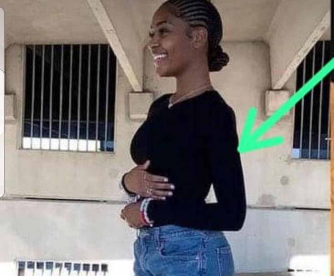 Woman wearing a fitted black V-neck long-sleeve top paired with blue jeans.